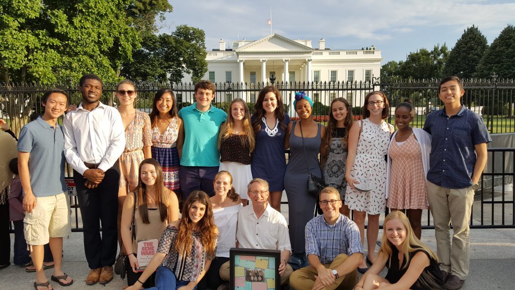 Group of young people posing for photo in front of fence in front of White House