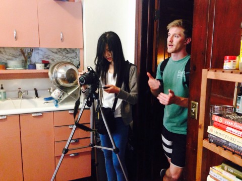 Two students work together behind a camera