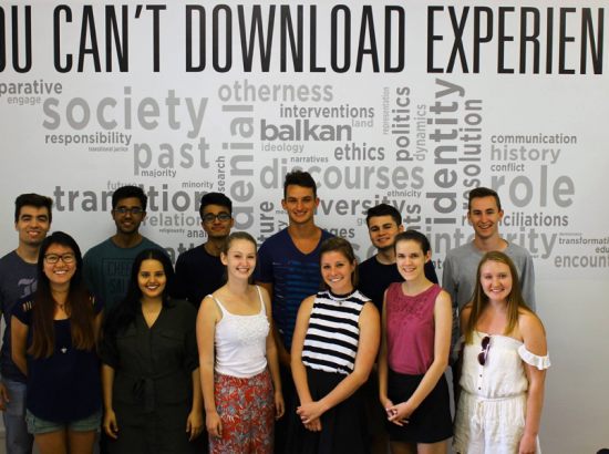 group of young people standing in front of a wall of inspiring words