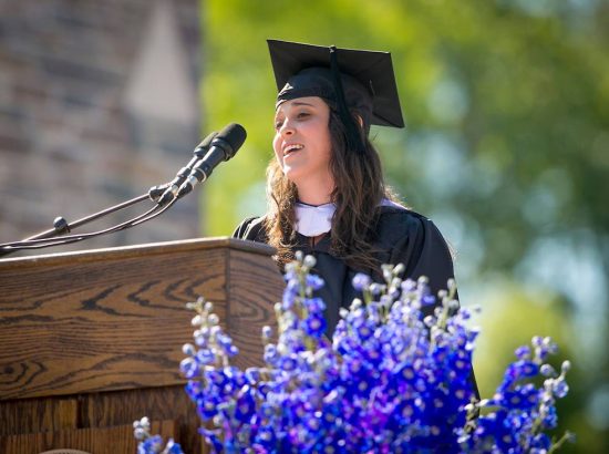 young woman in graduation gown at podium