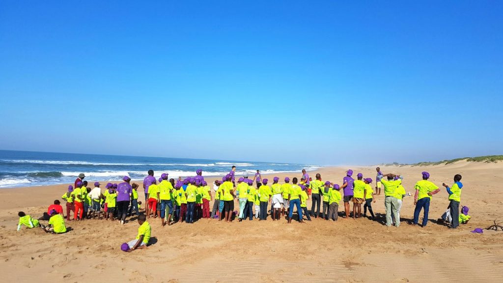 large group of young children in yellow shirt on a beach