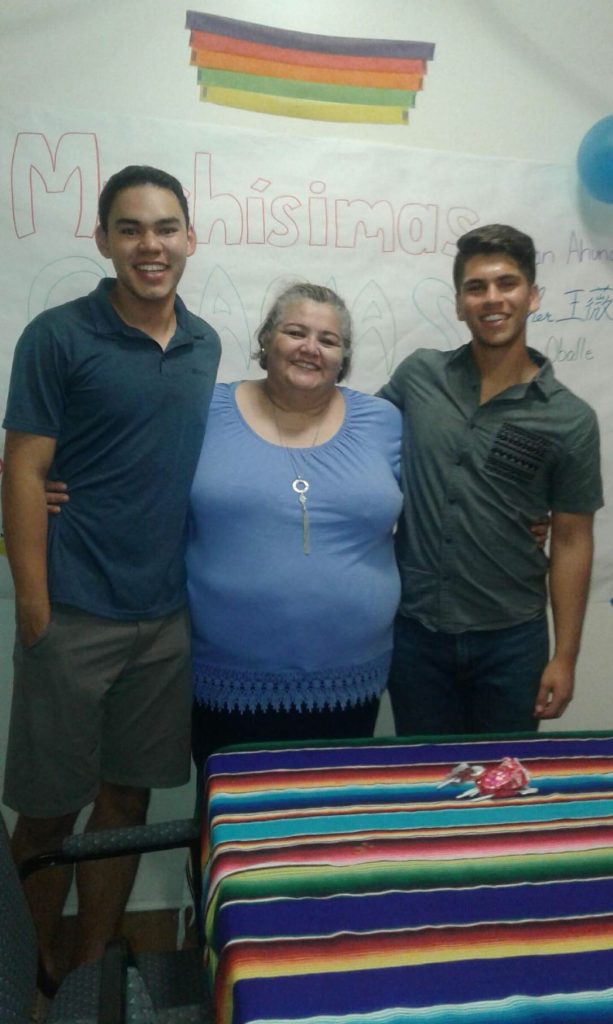two young men smiling with their host mother