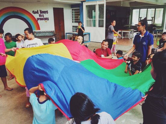 Children and staff hold rainbow parachute