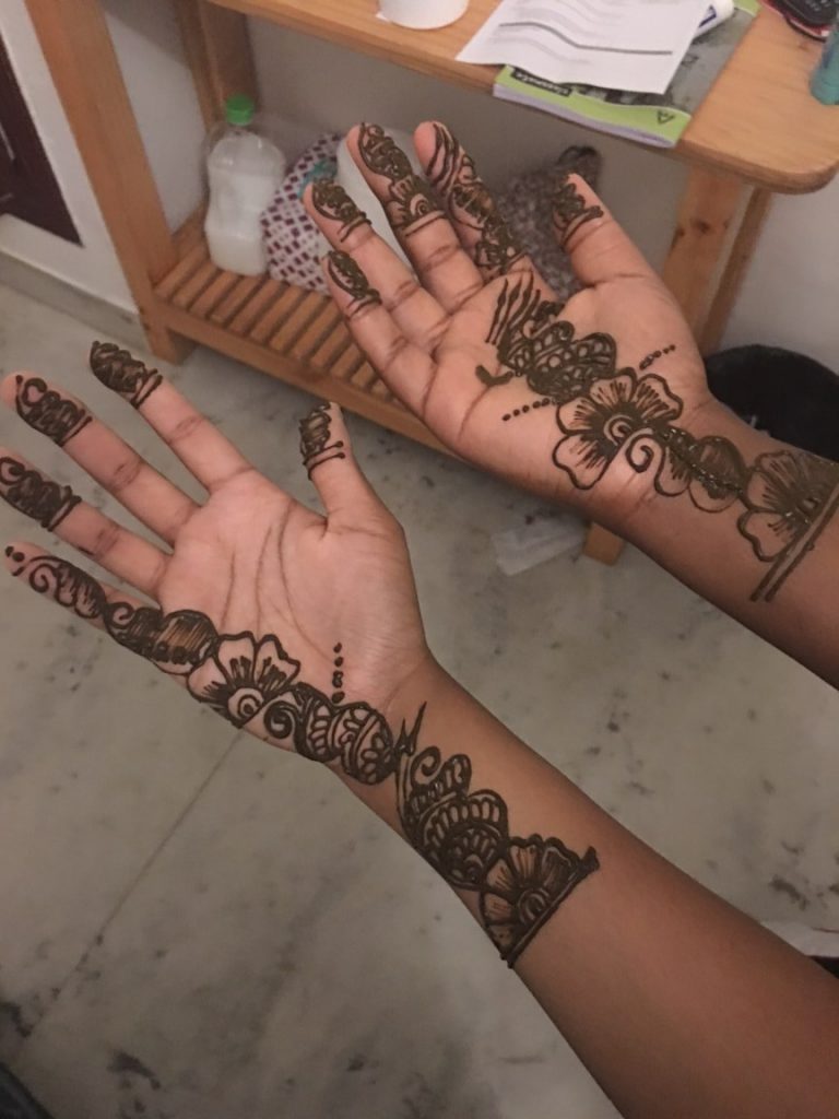 two hands with intricate henna designs