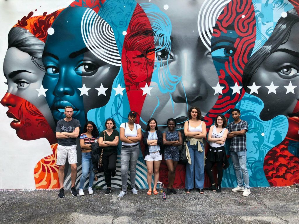 The group strikes a cross-armed pose in front of a mural on our second day in Miami.
