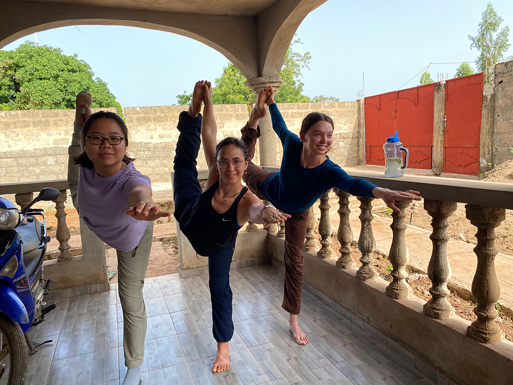 Three students doing dancer's pose on a porch