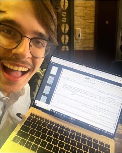 A man with an amused expression in front of a laptop with question marks on it