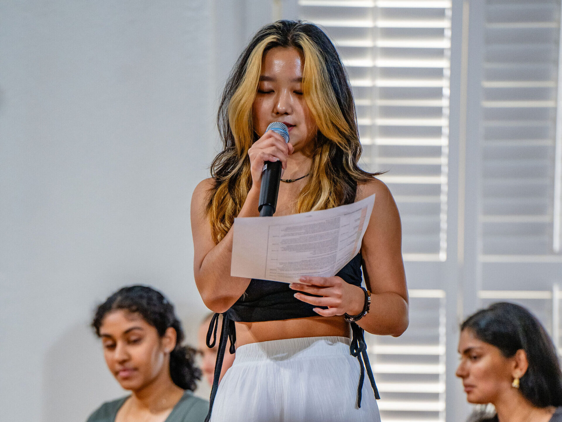 A young woman reads from a piece of paper