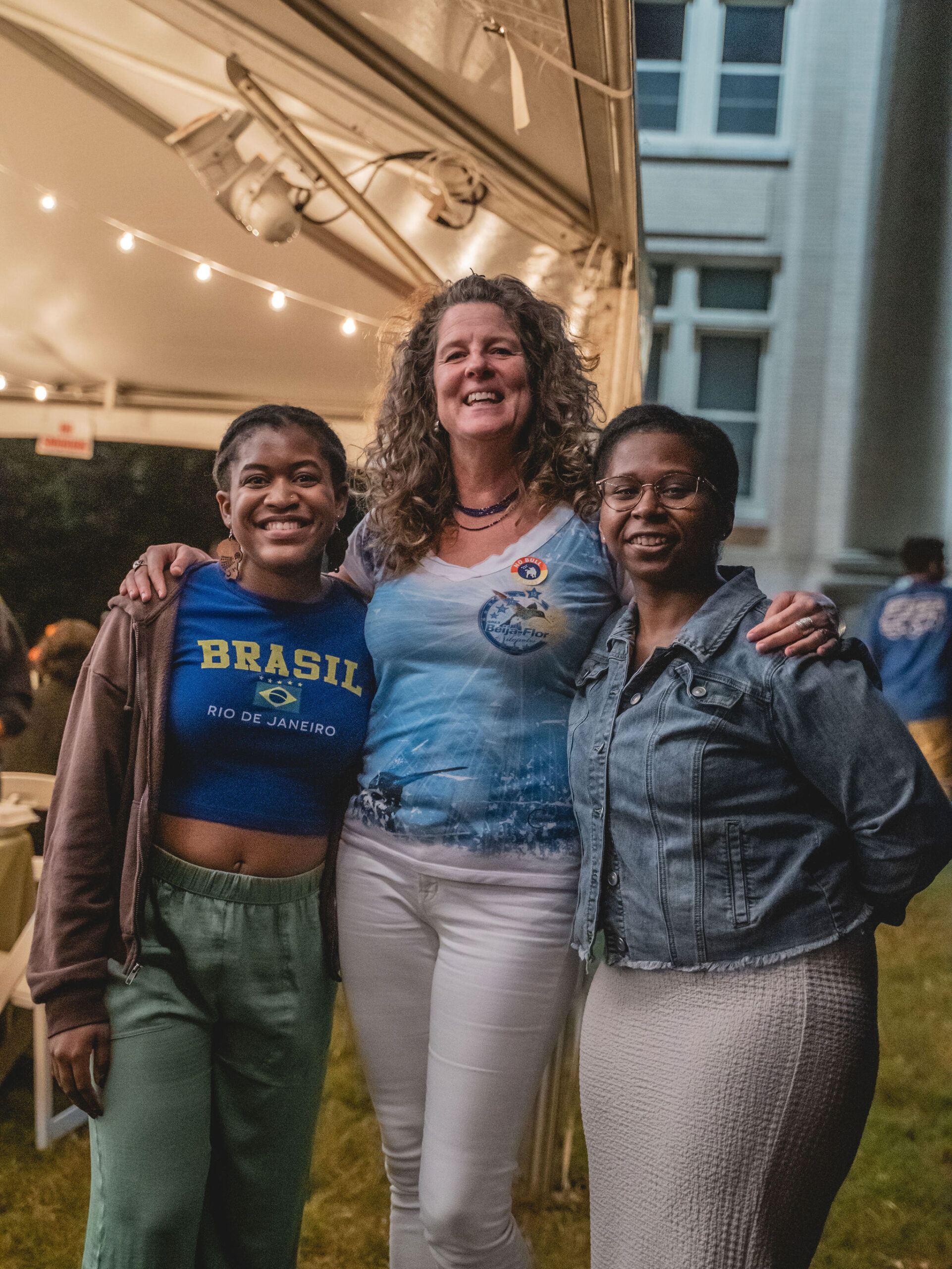 A woman stands with her arms around the shoulders of two students