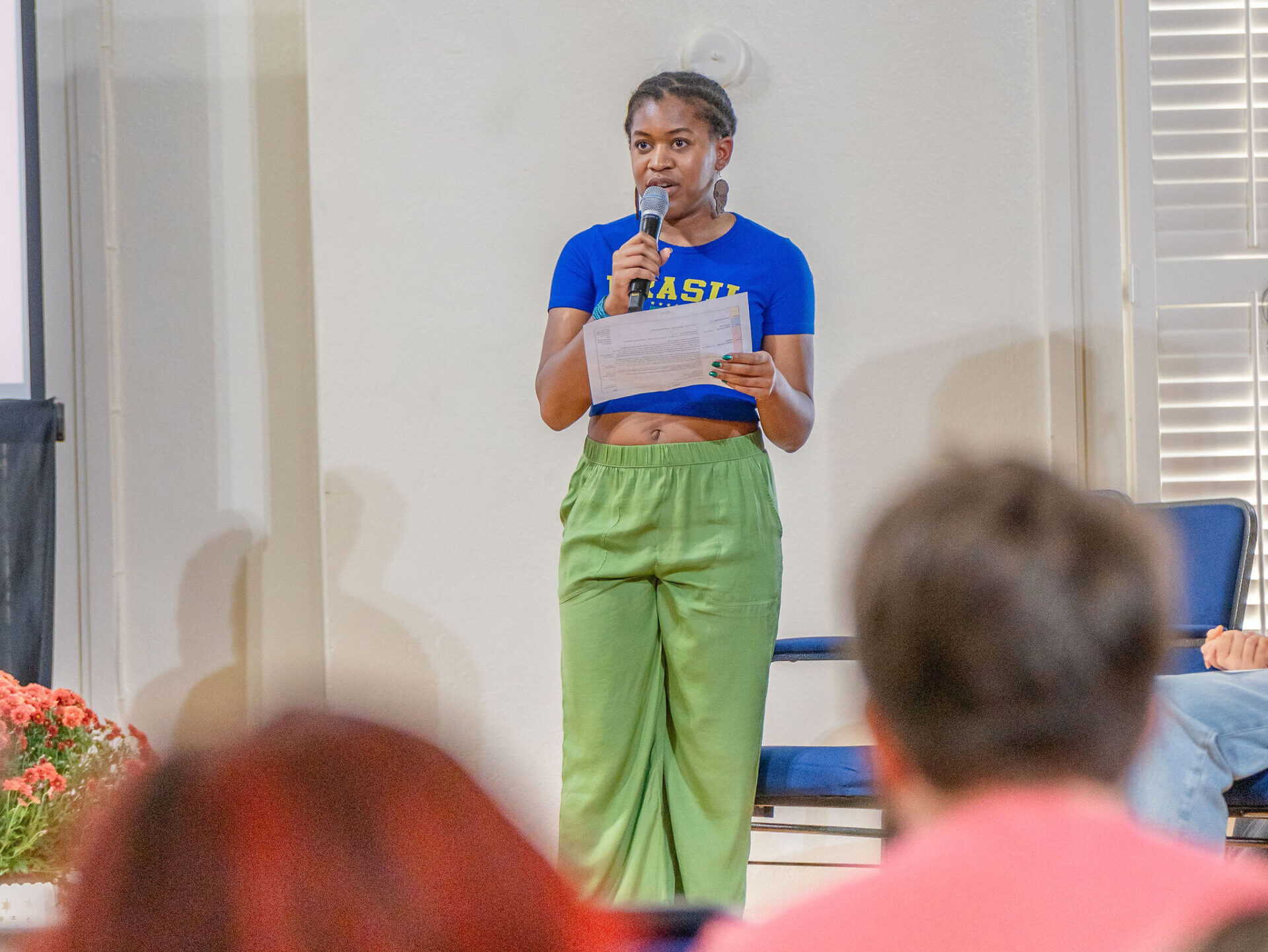 A young woman holds a microphone and speaks.