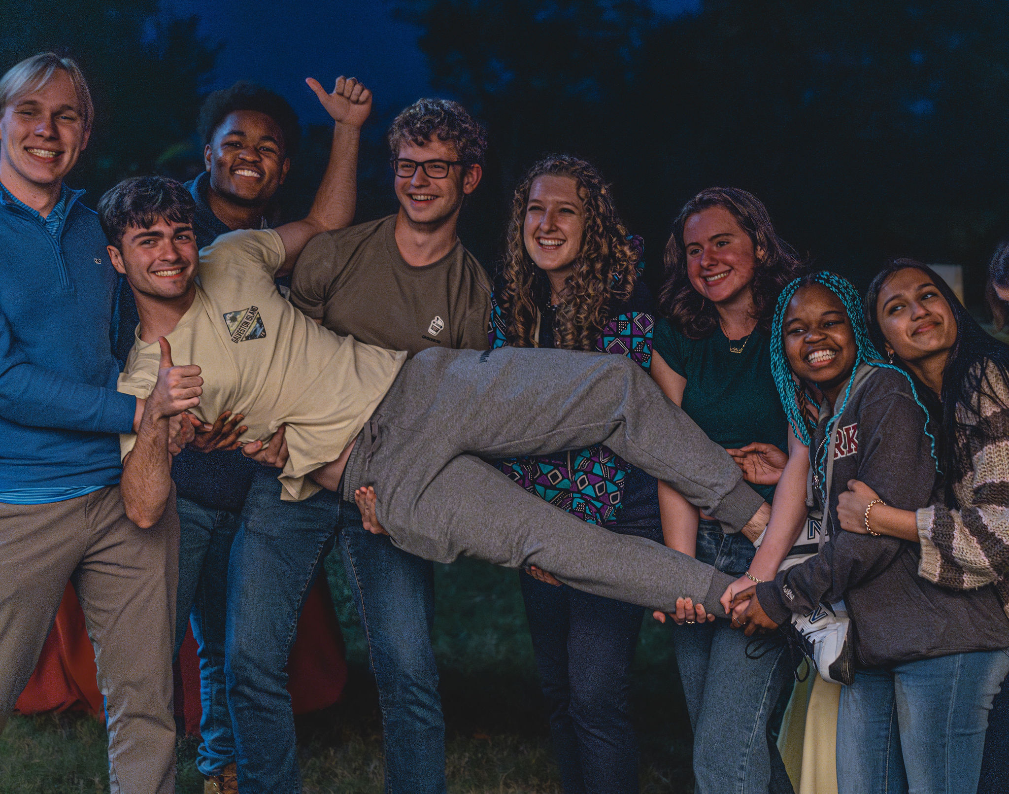 A group of students lifts a student into the air