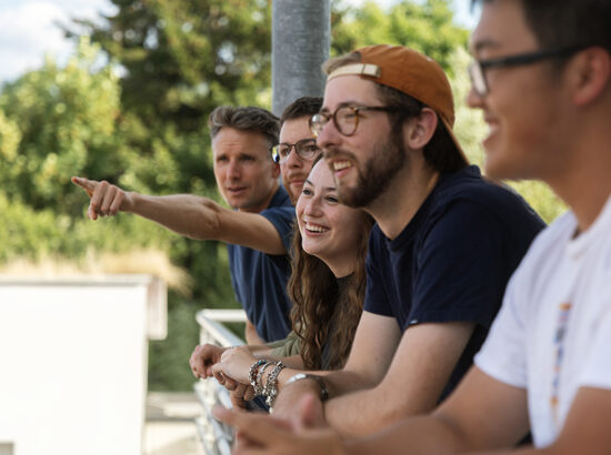 A man points out a sight to a group on a balcony