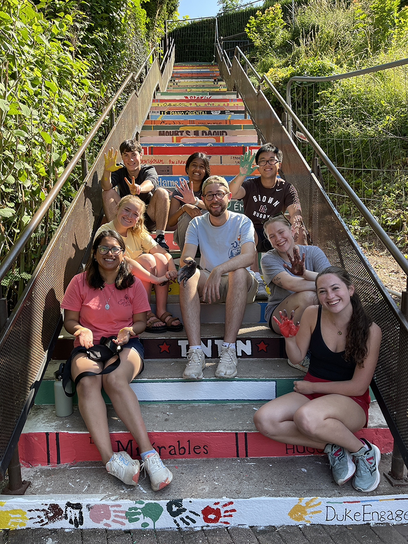A group of people smile as they sit on a painted staircase